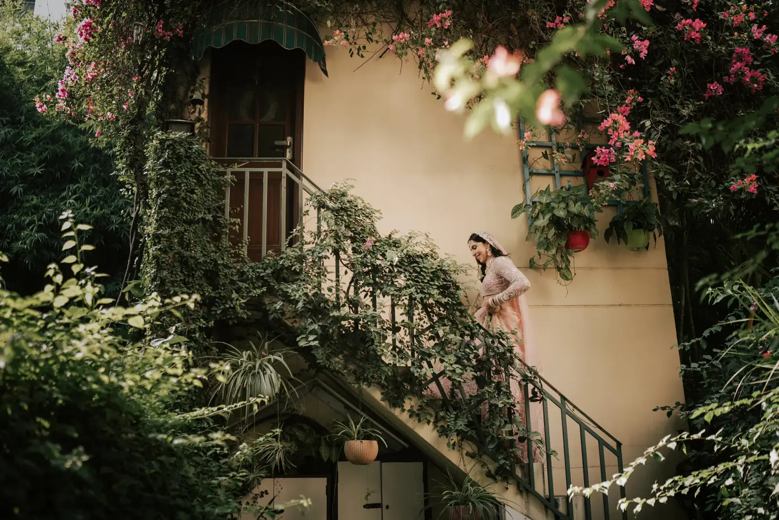 A bride on a garden staircase framed by bougainvillea