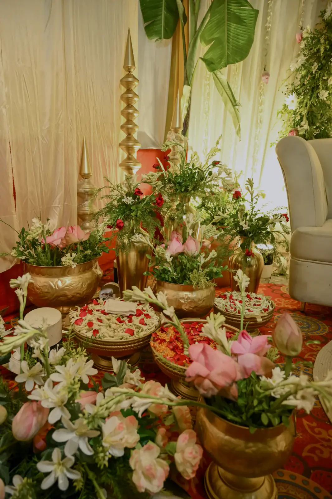 Brass urns, lilies and petal platters set before the stage