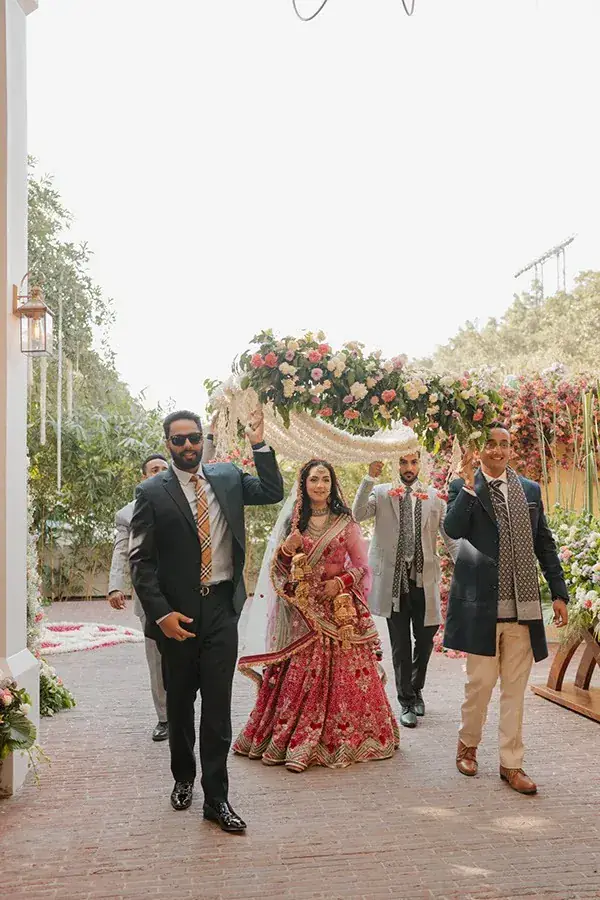 Aanandita arriving beneath a floral canopy carried above her